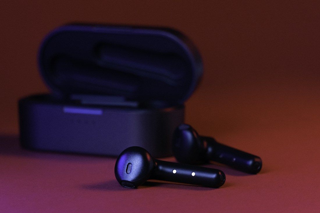 Wireless earbuds and charging case on a vivid background